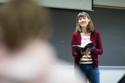 Sharon Marquart in the front of a classroom, holding a book. 