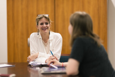 Lucie Holmgreen smiles at a student as they both sit at a table. 